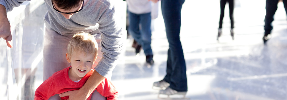 A man ice skating with his young son