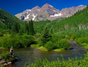 A fly fisherman with the Maroon Bells in the background