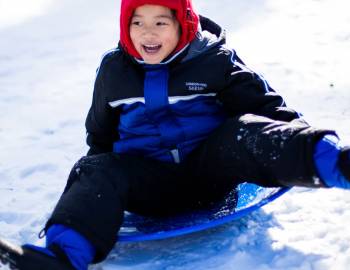 A child sledding down a snowy hill in Aspen