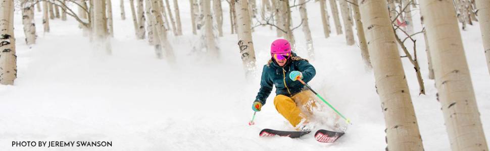 A skier dodging through trees during the winter