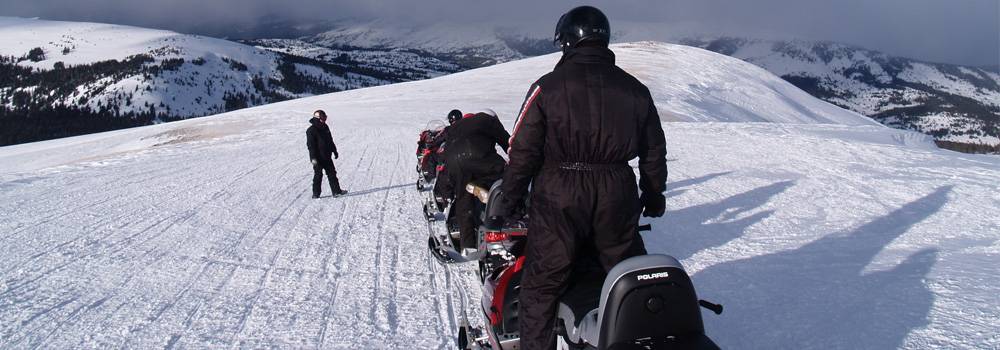 A group waiting single file on a snowmobile tour